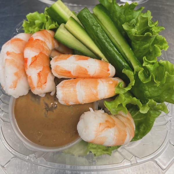 Shrimp, cucumber sticks, and lettuce with peanut sauce in a clear plastic container.