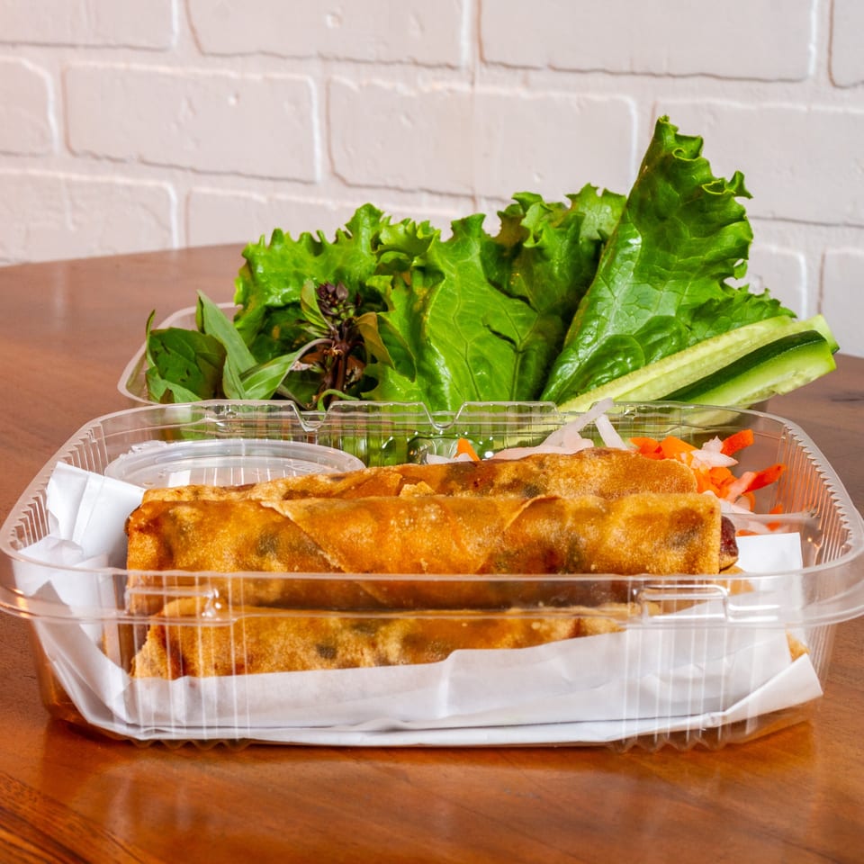 La Baguette Vietnamese Sandwiches' fried spring rolls with lettuce, herbs, and dipping sauce in plastic containers.